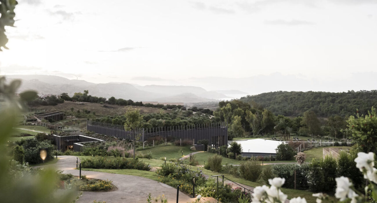 Scenic view of a winding path through lush greenery and hills under a cloudy sky.